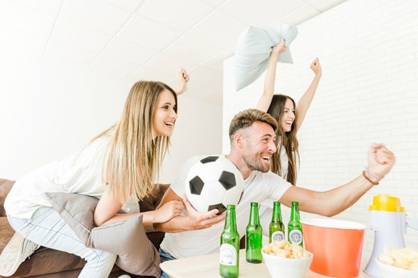 Hombre con 2 mujeres viendo un partido de fútbol y apostando